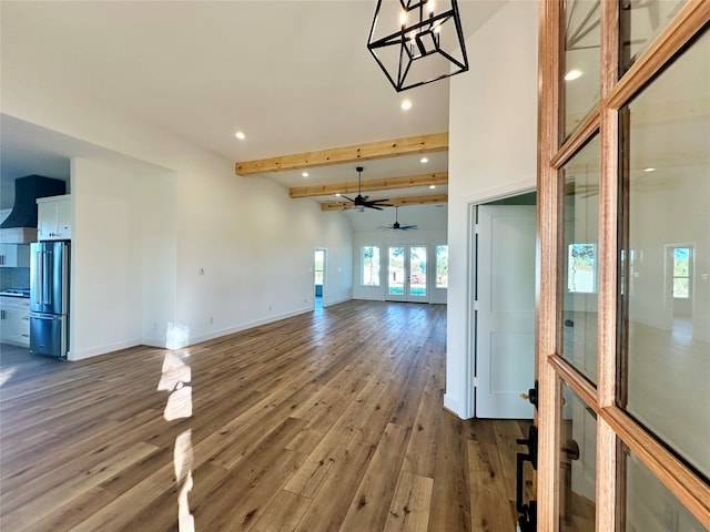 unfurnished living room with vaulted ceiling with beams, ceiling fan, and wood-type flooring