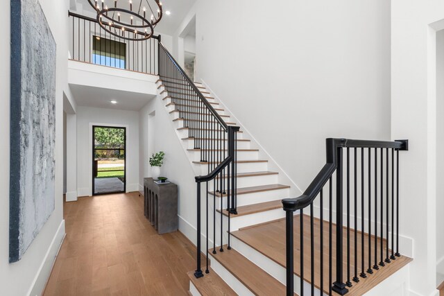 foyer with hardwood / wood-style flooring, a towering ceiling, and an inviting chandelier