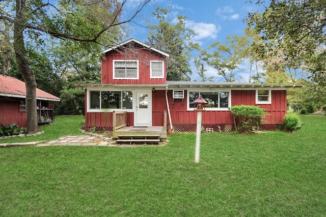 view of front of home featuring a wall mounted air conditioner and a front yard