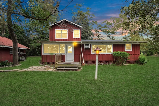 back house at dusk featuring a lawn