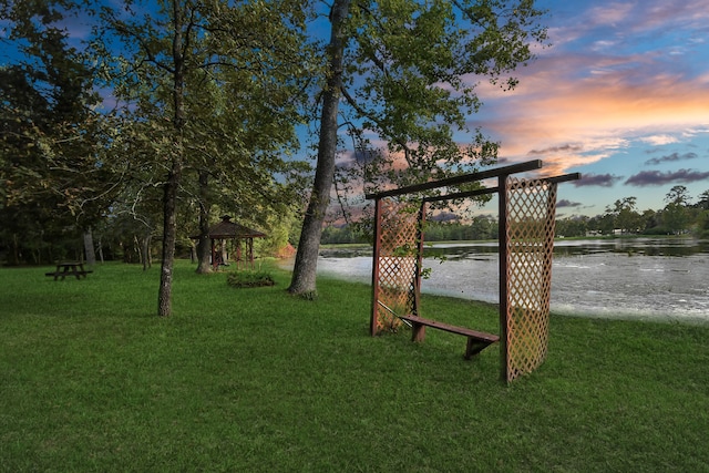 yard at dusk featuring a gazebo and a water view