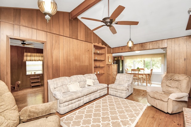 living room with vaulted ceiling with beams, ceiling fan, light hardwood / wood-style flooring, and wood walls