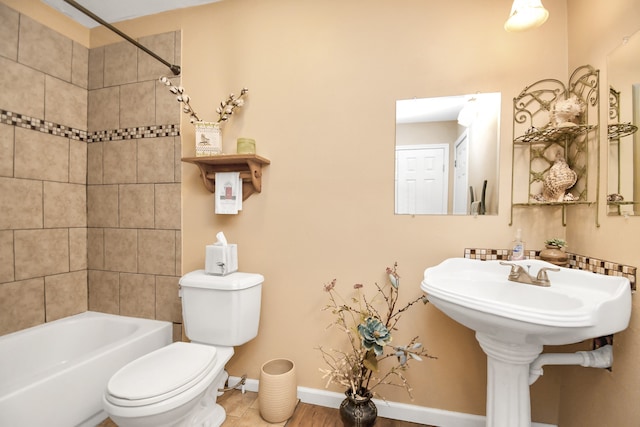 bathroom featuring hardwood / wood-style floors, tiled shower / bath combo, and toilet