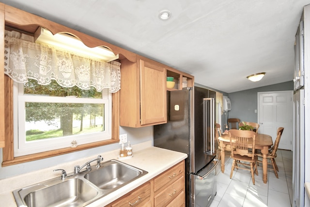 kitchen featuring high end refrigerator, sink, light tile patterned floors, and vaulted ceiling