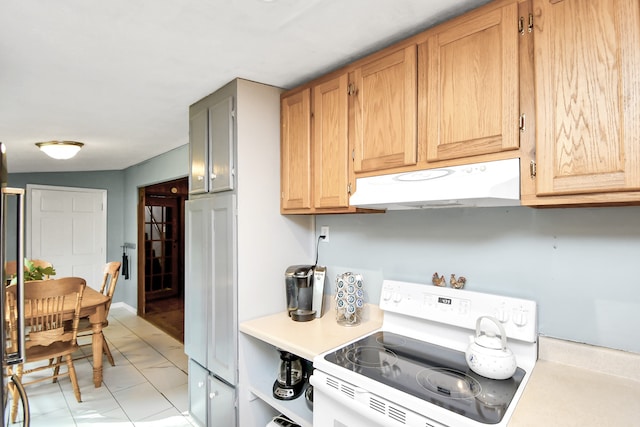 kitchen featuring white range oven, light tile patterned floors, and lofted ceiling