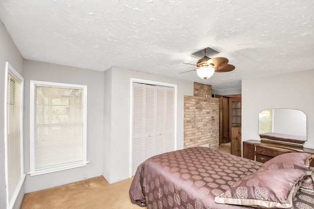 bedroom featuring a textured ceiling, ceiling fan, light carpet, and a closet