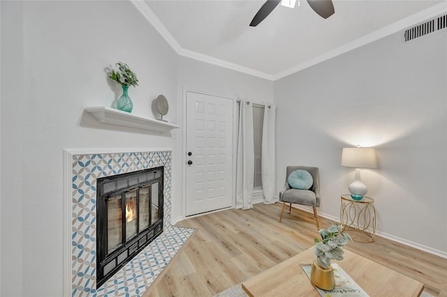 interior space with ceiling fan, a fireplace, light hardwood / wood-style flooring, and ornamental molding