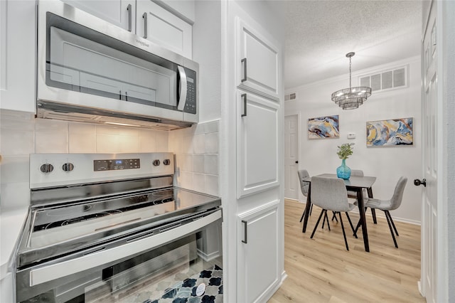 kitchen featuring tasteful backsplash, stainless steel appliances, pendant lighting, light hardwood / wood-style flooring, and white cabinets