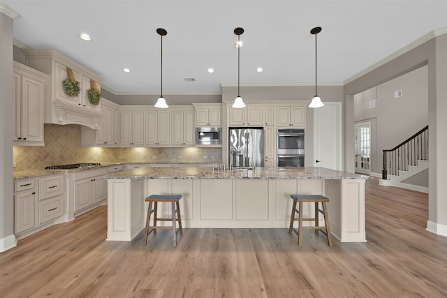 kitchen with decorative light fixtures, light stone countertops, stainless steel appliances, and a spacious island