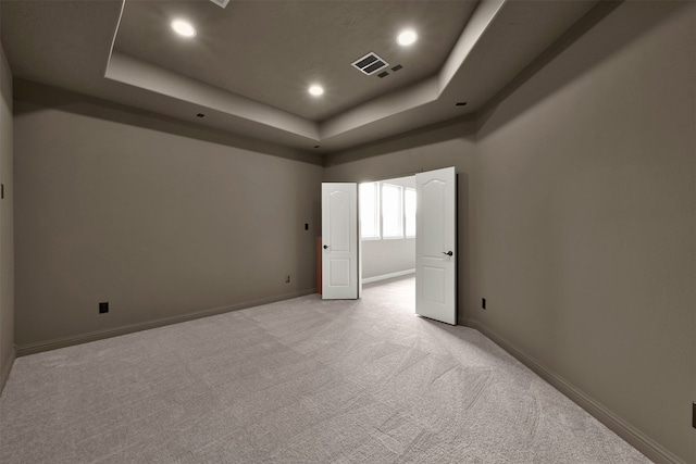 carpeted spare room featuring a raised ceiling