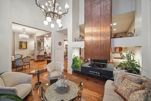 living room with wood-type flooring, a towering ceiling, and a notable chandelier