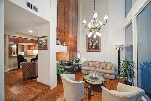 living room featuring hardwood / wood-style floors, a high ceiling, and an inviting chandelier