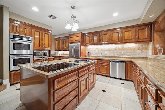 kitchen with an inviting chandelier, pendant lighting, decorative backsplash, a center island with sink, and appliances with stainless steel finishes