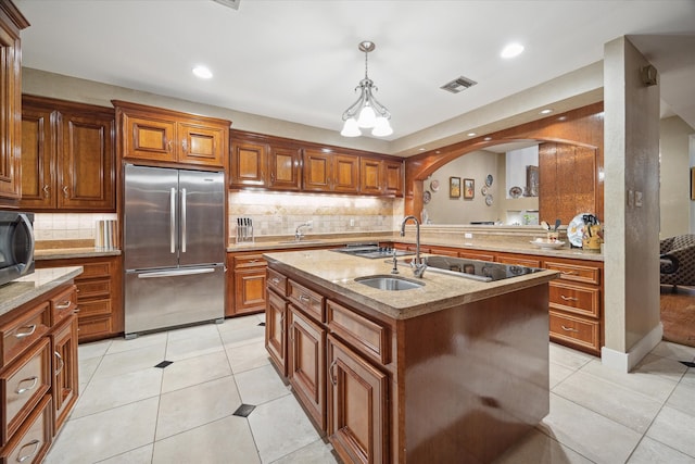 kitchen featuring sink, hanging light fixtures, stainless steel appliances, an island with sink, and light tile patterned floors