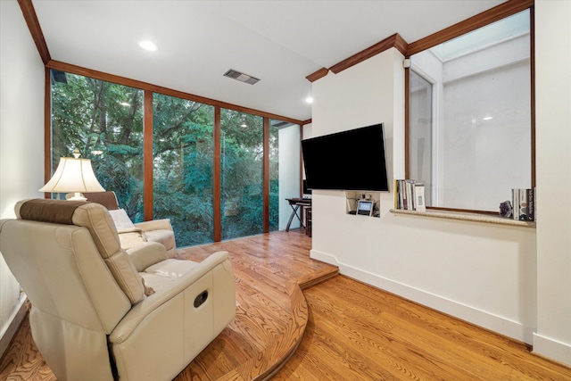 living room with light wood-type flooring, expansive windows, and ornamental molding