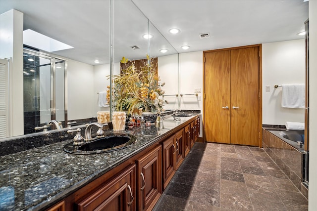 bathroom featuring vanity, plus walk in shower, and a skylight