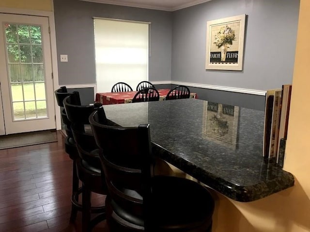 dining room with crown molding, a healthy amount of sunlight, and dark hardwood / wood-style floors