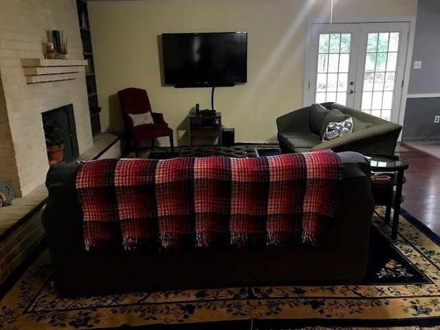 living room with wood-type flooring, a brick fireplace, and french doors