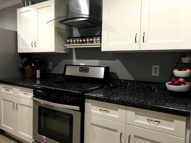 kitchen with stainless steel gas range, dark stone countertops, crown molding, white cabinets, and exhaust hood