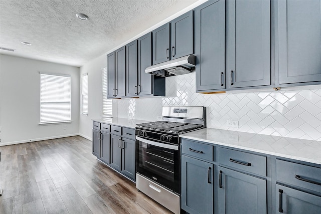 25342 Trinity Oakley Ct, Katy, TX 77493 - kitchen with gas stove, under cabinet range hood, tasteful backsplash, a textured ceiling, and dark wood-type flooring