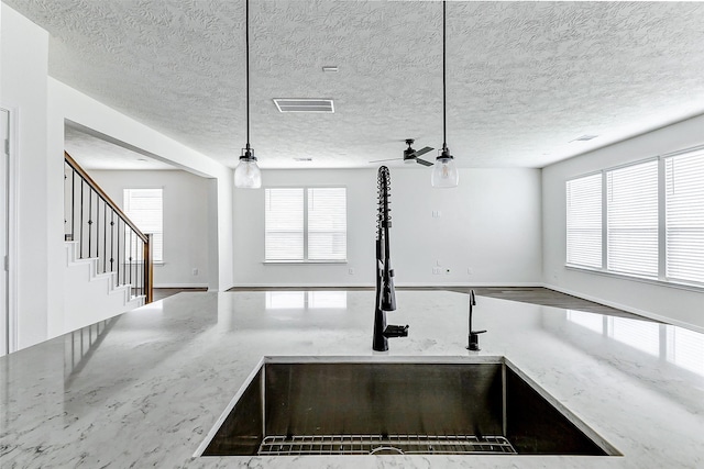 25342 Trinity Oakley Ct, Katy, TX 77493 - kitchen view of a sink, light stone counters, pendant lighting, and a textured ceiling