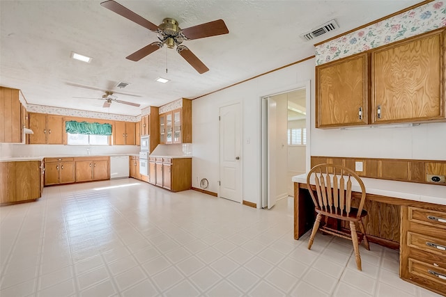 kitchen featuring white appliances, built in desk, a wealth of natural light, and ceiling fan