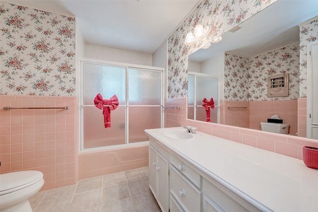 full bathroom featuring tile patterned flooring, toilet, shower / bath combination with glass door, and tile walls