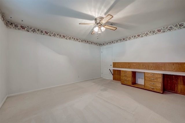 carpeted empty room with ceiling fan and built in desk