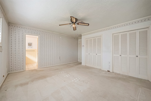 unfurnished bedroom with multiple closets, ceiling fan, light carpet, and a textured ceiling