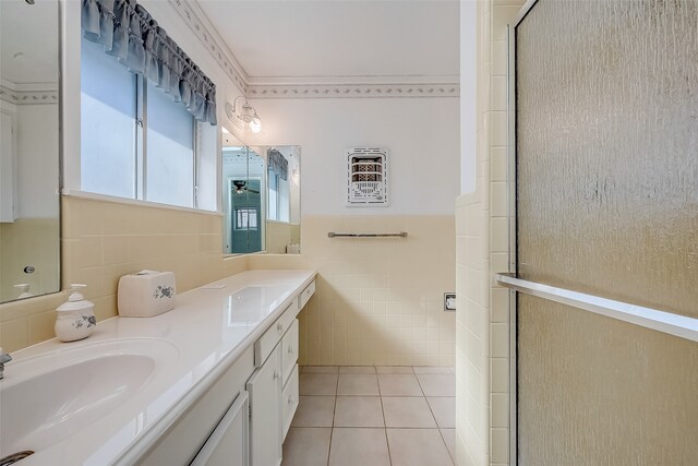 bathroom with tile patterned floors, vanity, a shower with shower door, and tile walls