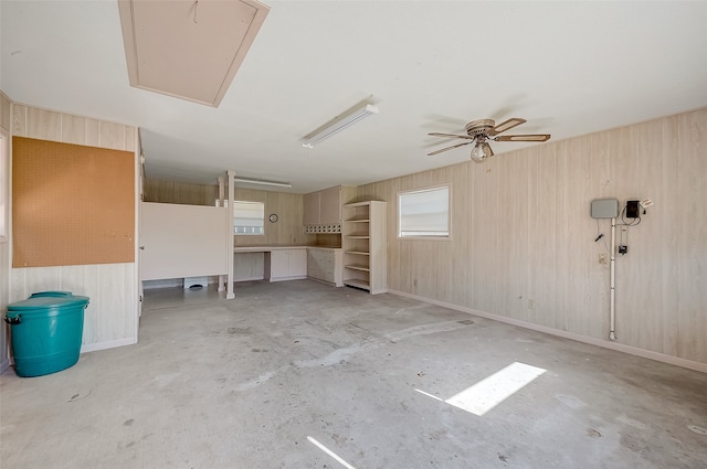 interior space featuring ceiling fan and wooden walls