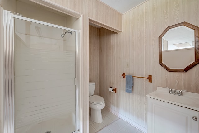 bathroom with vanity, wooden walls, tile patterned flooring, toilet, and a shower with shower door