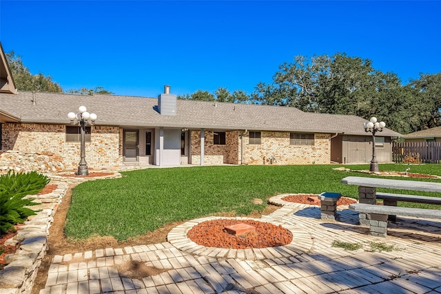 rear view of house with a lawn, a patio, and a fire pit