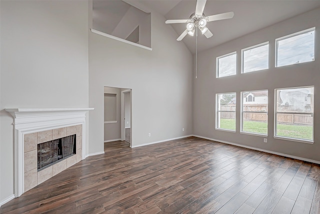 unfurnished living room featuring ceiling fan, a tile fireplace, dark wood-type flooring, and high vaulted ceiling