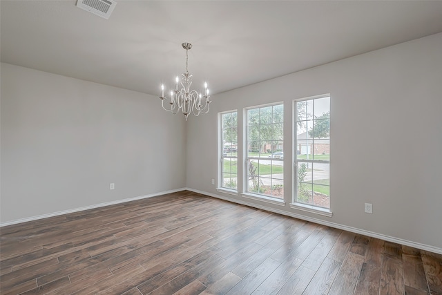 unfurnished room featuring a notable chandelier, dark wood-type flooring, and a wealth of natural light