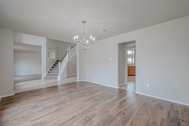 unfurnished room featuring a chandelier and light hardwood / wood-style floors