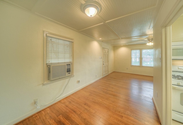 empty room featuring cooling unit, light hardwood / wood-style flooring, ceiling fan, and ornamental molding