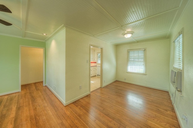 empty room featuring cooling unit, wood-type flooring, baseboards, and crown molding