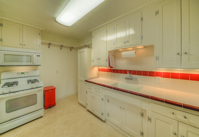 kitchen featuring white appliances, a sink, white cabinets, and decorative backsplash