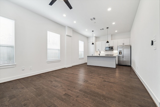 kitchen featuring pendant lighting, white cabinets, an island with sink, dark hardwood / wood-style flooring, and stainless steel appliances