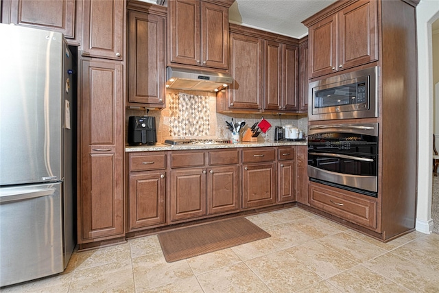 kitchen featuring light stone counters, stainless steel appliances, and decorative backsplash