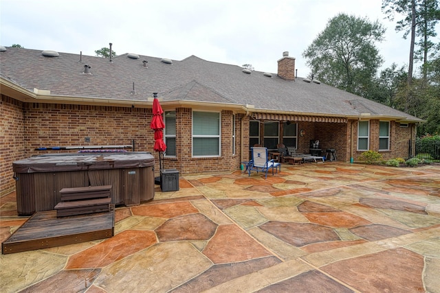 rear view of house featuring a patio area and a hot tub