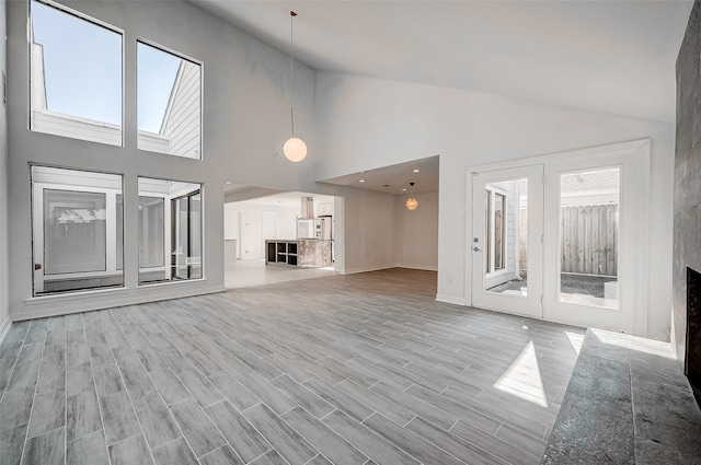 unfurnished living room featuring high vaulted ceiling and light wood-type flooring