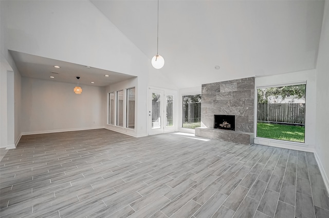 unfurnished living room featuring light wood-type flooring, a large fireplace, and high vaulted ceiling