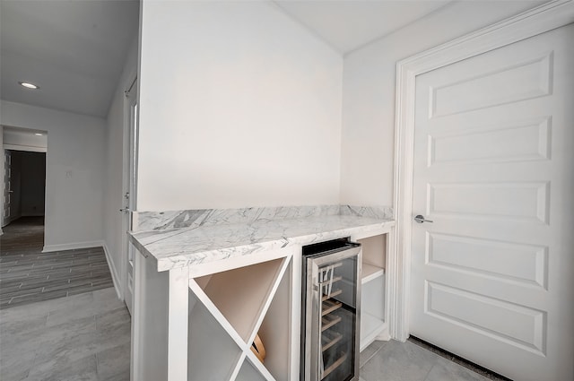 bar featuring light stone counters, light wood-type flooring, and wine cooler