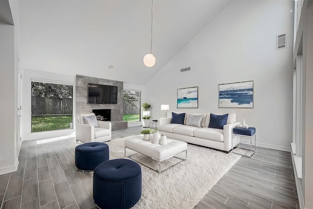 living room featuring a high end fireplace, hardwood / wood-style floors, and high vaulted ceiling