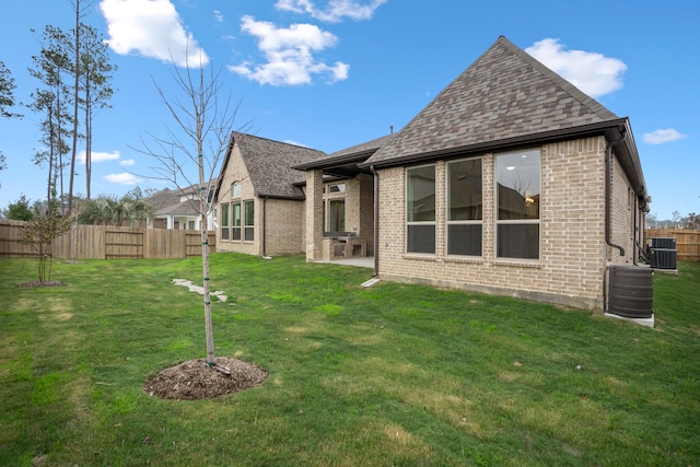 back of house featuring a lawn and central air condition unit