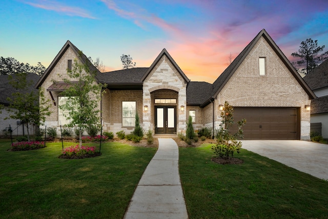 view of front of house featuring a lawn, a garage, and french doors