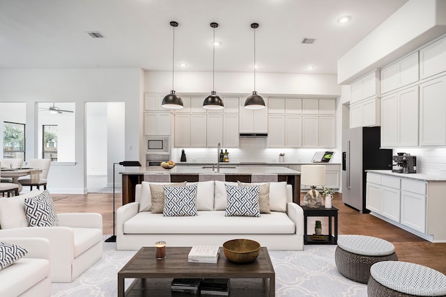 living room with hardwood / wood-style flooring, ceiling fan, and sink