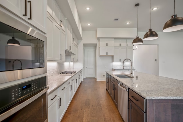 kitchen featuring appliances with stainless steel finishes, light hardwood / wood-style flooring, white cabinetry, and pendant lighting